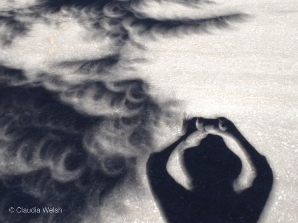 Self-portrait with crescent-shaped tree shadows during the eclipse, by Claudia Welsh