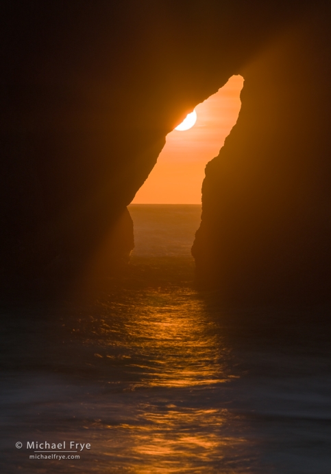 Sun setting through an arch, Oregon Coast, USA