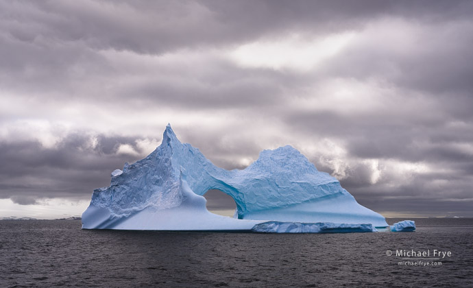Iceberg, arch, and clouds, Antarctica